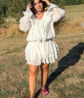 Femme en robe blanche fluide zenoya-paris souriant dans un champ en été près de paris sous un ciel bleu